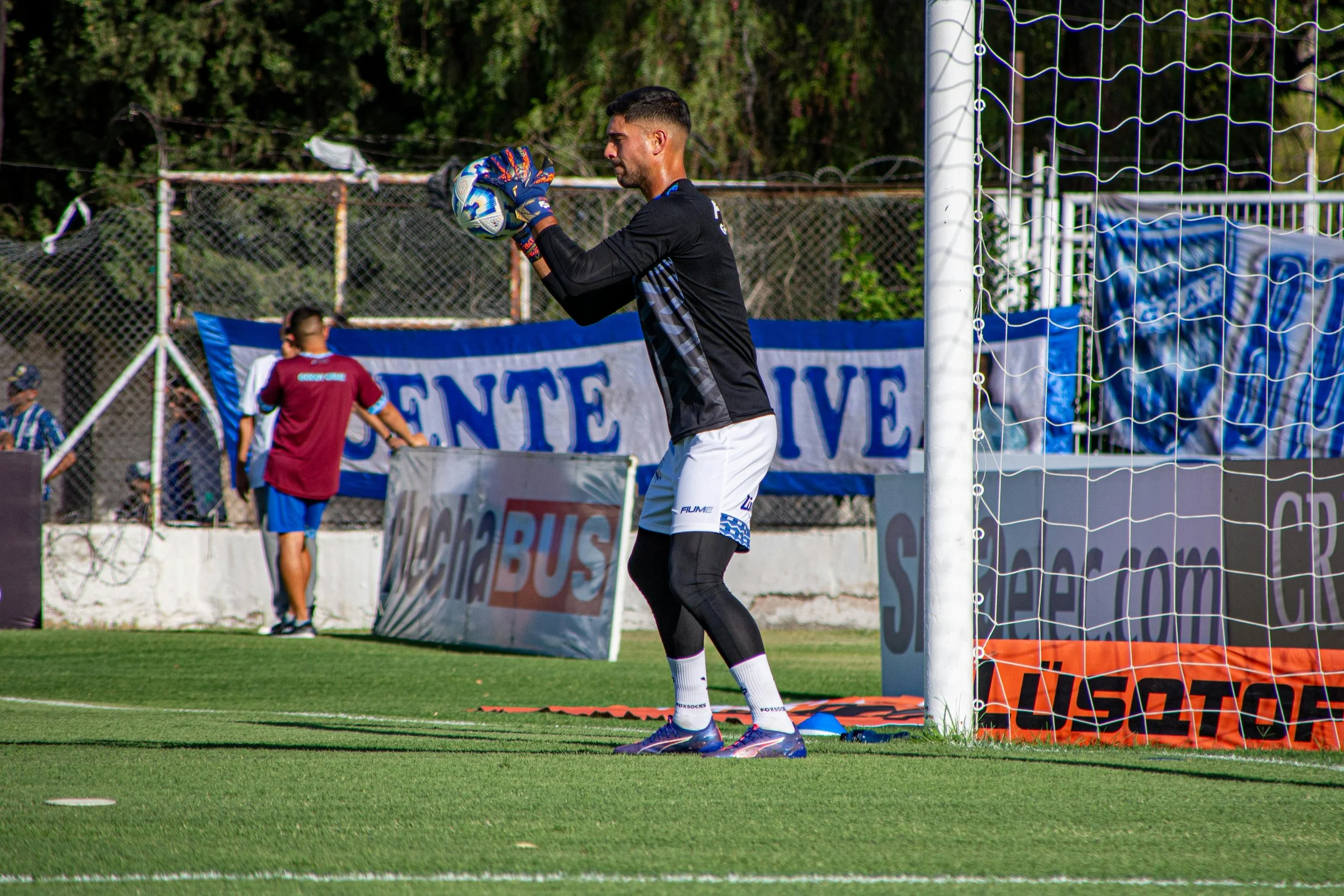 A soccer goalkeeper holding a soccer ball during a game on a grass field
