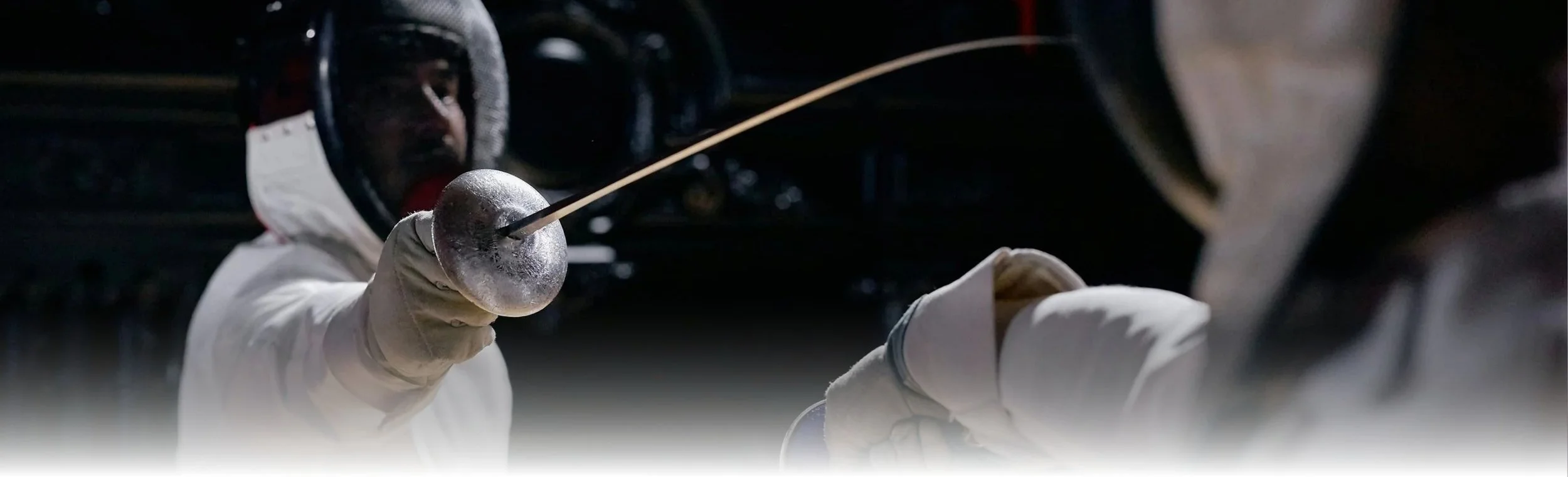 A person wearing a helmet and holding a tennis ball with a long pick during the night.